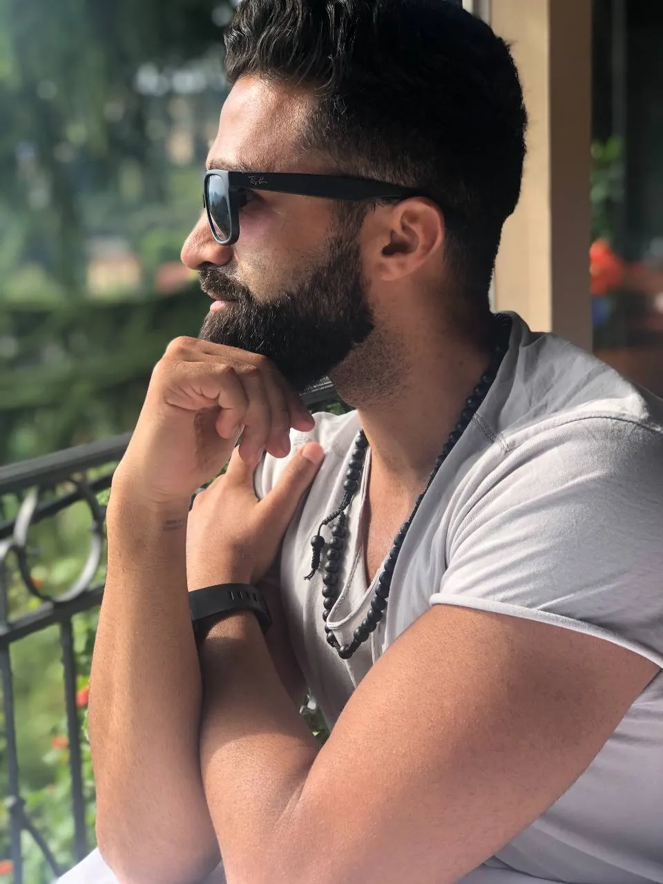 Sohrab Papahn im Profil mit Sonnenbrille, das Kinn auf die Hand gestützt, auf einem Balkon